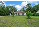A single-story home with a green front door and garage, complemented by a large grassy yard at 21168 Sw Peach Blossom St, Dunnellon, FL 34431
