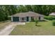 A cozy single-story home with a green garage door and front door is highlighted by an expansive lawn at 21168 Sw Peach Blossom St, Dunnellon, FL 34431