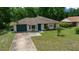 A single-story home with a green front door and garage, showcasing a well-maintained lawn at 21168 Sw Peach Blossom St, Dunnellon, FL 34431