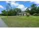 A charming single-story home with a green garage door and front door, complemented by a spacious lawn at 21168 Sw Peach Blossom St, Dunnellon, FL 34431