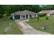 View of a cozy home with a driveway, green garage door, mature landscaping, and green lawn at 21168 Sw Peach Blossom St, Dunnellon, FL 34431