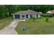 Charming single-story home with a well-maintained lawn, green garage door and mature trees at 21168 Sw Peach Blossom St, Dunnellon, FL 34431