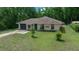 A charming home featuring a green garage door, lush greenery, and a well-manicured lawn at 21168 Sw Peach Blossom St, Dunnellon, FL 34431