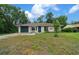 Charming single-story home featuring an attached garage, manicured lawn, and lush, mature trees at 21168 Sw Peach Blossom St, Dunnellon, FL 34431