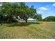 Expansive green lawn gently sloping towards the lake, framed by mature trees, creating a serene landscape at 21168 Sw Peach Blossom St, Dunnellon, FL 34431