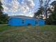 Back view of a quaint blue single-story home with a sliding glass door to the yard at 263 Oak Lane Trak, Ocala, FL 34472