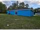 Rear view of a delightful blue single-story home with a sliding glass door leading to the backyard at 263 Oak Lane Trak, Ocala, FL 34472