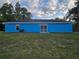 Back view of a charming blue single-story home with a sliding glass door and a well kept lawn at 263 Oak Lane Trak, Ocala, FL 34472