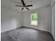 Bedroom with ceiling fan, gray wood floors, and large window providing natural light at 263 Oak Lane Trak, Ocala, FL 34472