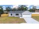 Single-story home featuring a two-car garage, a well-maintained lawn and a wooden fence at 28 Olive Dr, Ocala, FL 34472