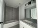 Modern bathroom featuring a tub with tiled walls, granite countertop, and a stylish vanity at 4162 Sw Gardenia Ct, Dunnellon, FL 34431