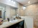 Well-lit bathroom featuring a large mirror, tiled shower, granite countertop, and under-sink dark brown cabinets at 5092 Sw 197Th Ter, Dunnellon, FL 34431