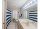 Neutral bathroom featuring large mirror, white tile and shower with blue and white shower curtain at 9 Fir Trail Pass, Ocala, FL 34472