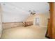 Spacious carpeted loft area with a wooden railing, ceiling fan, and access to other rooms in the house at 950 Sw 43Rd Pl, Ocala, FL 34471