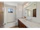 Bathroom featuring a tub with shower, window, vanity with dark wood cabinet and mirror at 10197 Sw 88Th Ter, Ocala, FL 34481