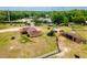This aerial view showcases a home, outbuildings, and a sprawling property with a paddock ready for animals at 10631 W Highway 40, Ocala, FL 34482