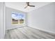 Bright bedroom with light gray walls, wood-look floors, large window and ceiling fan at 13493 Sw 112 Pl, Dunnellon, FL 34432