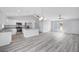 Bright living room features wood-look flooring, large window, and white kitchen with stainless steel appliances at 13493 Sw 112 Pl, Dunnellon, FL 34432