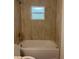 Bathroom tub and shower with neutral toned tile surround and a small window at 2871 Se 145 Pl, Summerfield, FL 34491