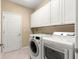 Laundry room featuring front-loading washer and dryer, white cabinets, and tile flooring at 5616 Nw 39Th Ln, Ocala, FL 34482
