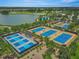 Aerial view of the community's six tennis courts near a lake and golf course, ideal for active living at 5616 Nw 39Th Ln, Ocala, FL 34482