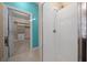 Bright shower with white tiles and glass door, next to a closet featuring built-in shelves at 6376 Sw 97Th Terrace Rd, Ocala, FL 34481