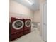 Efficient laundry room featuring modern red front-loading washer and dryer, and utility sink at 6376 Sw 97Th Terrace Rd, Ocala, FL 34481