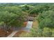 Scenic aerial view of a home nestled among lush trees with a long driveway and a glimpse of a playground at 660 Silver Pass, Ocala, FL 34472