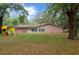 View of backyard with mature trees, a playset, and rear of the house at 660 Silver Pass, Ocala, FL 34472