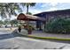 Exterior view of the building entrance, accented by a striped awning, potted plants, and manicured shrubs at 660 Silver Pass, Ocala, FL 34472