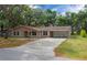 Ranch-style home with a long driveway, mature trees, and a two-car garage at 660 Silver Pass, Ocala, FL 34472