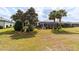 A generous backyard features mature trees, well-kept grass, and a large screened-in lanai with an umbrella-shaded table at 7455 Sw 97Th Terrace Rd, Ocala, FL 34481