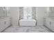 Bright bathroom with marble floors featuring a soaking tub between two large vanities at 7585 Nw 33Rd Pl, Ocala, FL 34482