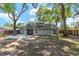 Spacious backyard surrounded by mature trees, a covered patio, and white rock landscaping at 8 Banyan Dr, Ocala, FL 34472