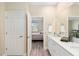 Bathroom with double sinks, quartz counters, wood-look flooring, and view into bedroom at 9923 Sw 98Th Ln, Ocala, FL 34481