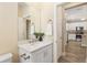 Powder room with a white vanity, granite countertop, and a view to the kitchen at 9923 Sw 98Th Ln, Ocala, FL 34481