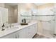 Bathroom featuring a double sink vanity, white tiled shower with a glass door, and wood-look floors at 9923 Sw 98Th Ln, Ocala, FL 34481
