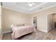 Bright bedroom with ensuite bathroom, wood-look flooring, and a tray ceiling with fan at 9923 Sw 98Th Ln, Ocala, FL 34481