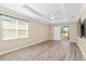 Bright bedroom with tray ceiling, fan, wood-look flooring, and sliding door access to the lanai at 9923 Sw 98Th Ln, Ocala, FL 34481