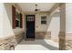 Inviting front porch with stone accents, a modern light fixture, and a stylish black front door with glass inserts at 9923 Sw 98Th Ln, Ocala, FL 34481