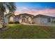 Charming single-story home with arched windows, well-maintained lawn, and beautiful landscaping at sunset at 5245 Nw 21St Loop, Ocala, FL 34482
