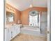 Well-lit bathroom featuring a soaking tub, glass block window, and a separate shower at 5245 Nw 21St Loop, Ocala, FL 34482