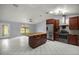 Bright kitchen with an island, stainless steel appliances, dark cabinets, and white-tiled floor at 14171 Sw 8Th Ave, Ocala, FL 34473