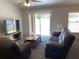 Bright living room with sliding glass doors, ceiling fan, and leather reclining sofa and chair for relaxing evenings at 15266 Sw 44Th Ter, Ocala, FL 34473