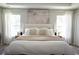 Bright bedroom featuring a large bed with neutral decor, windows, and tray ceiling at 18 Larch Radl, Ocala, FL 34480