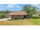 A brick house features a well-kept lawn, mature trees, and an inviting driveway on a bright, sunny day at 2045 Se 32Nd St, Ocala, FL 34471