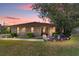 Charming brick home with well-manicured lawn, bushes, and a beautiful tree in the front yard at sunset at 2045 Se 32Nd St, Ocala, FL 34471