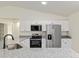 Kitchen boasts granite countertops, stainless steel appliances, and sleek white cabinetry at 24375 Nw Foxglove Ln, Dunnellon, FL 34431