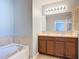 Bright bathroom with dual sinks and a soaking tub with a tiled surround at 4013 Ruby Run, Haines City, FL 33844