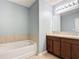 Bathroom features a pristine white tub, tile detail, modern fixtures, and wood cabinetry at 4013 Ruby Run, Haines City, FL 33844
